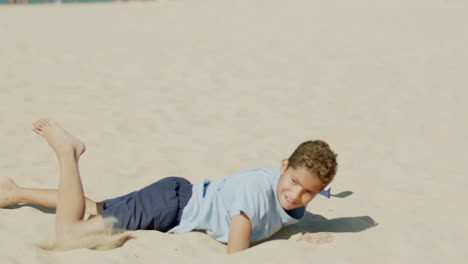 Side-view-of-focused-boy-kicking-ball-in-jump-on-summer-day