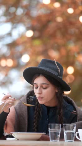 woman eating soup outdoors in autumn