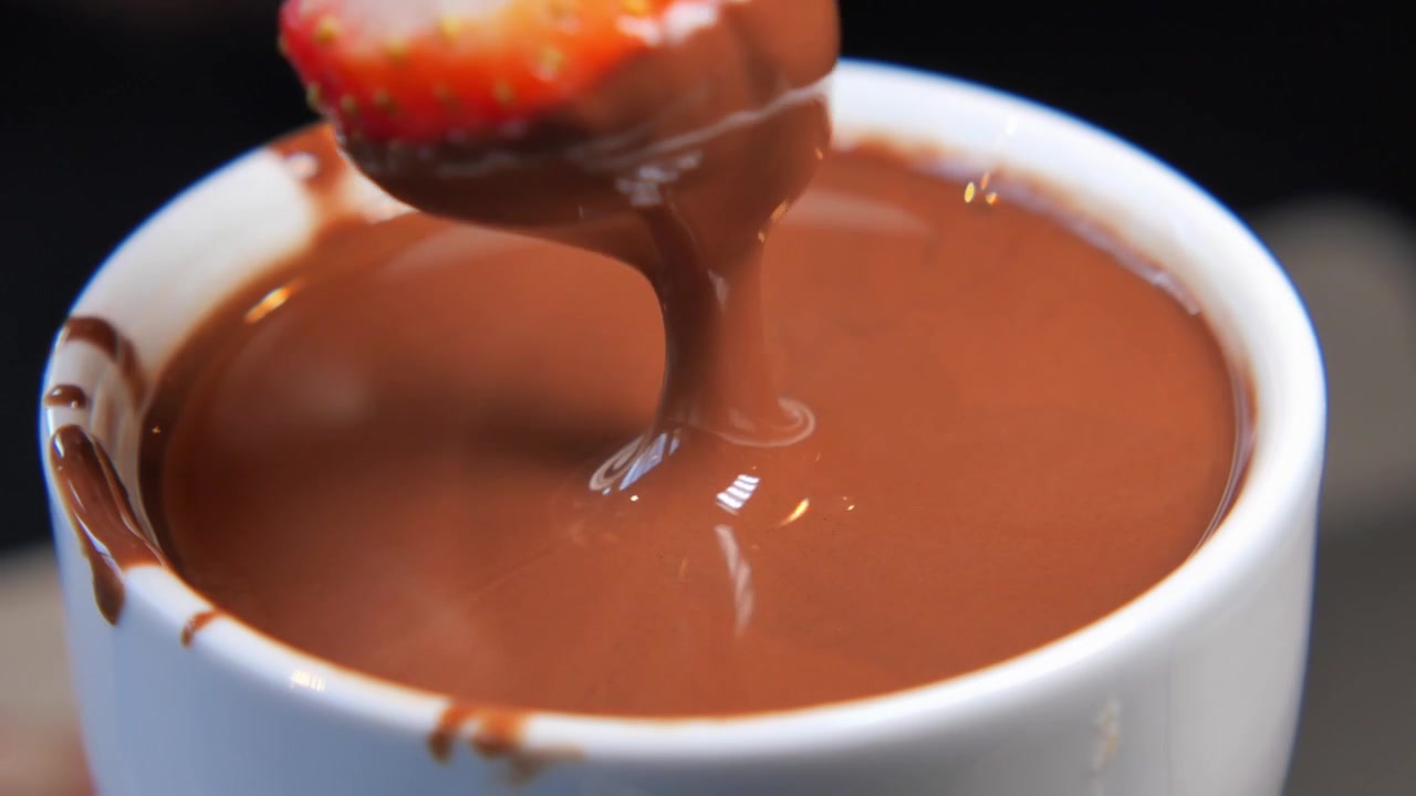 Fragola fresca immersa nella fonduta di cioccolato fuso