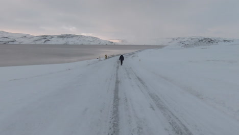 dolly vorwärts, mädchen geht langsam auf leerer, rutschiger straße, winterlandschaft