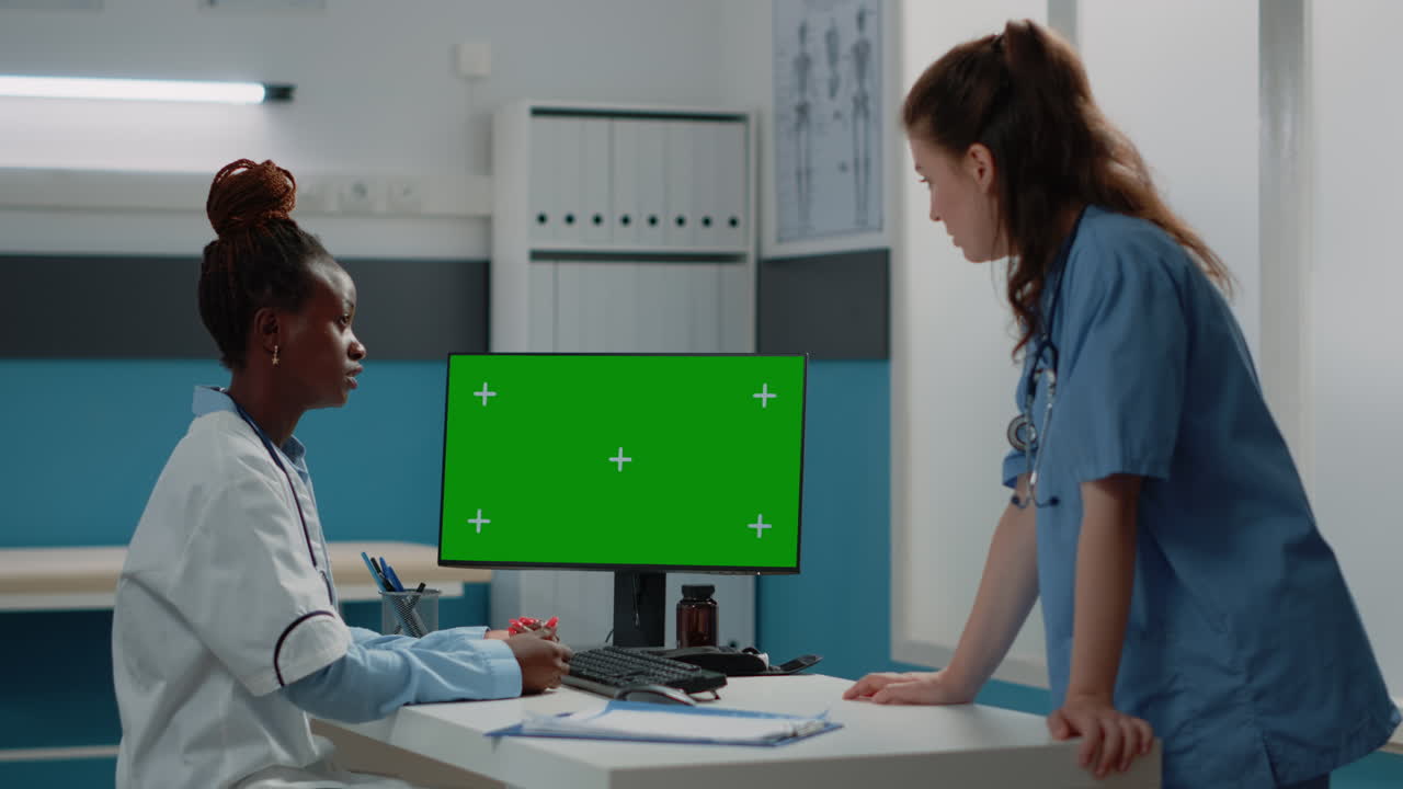 Doctors discussing patient information on computer with green screen