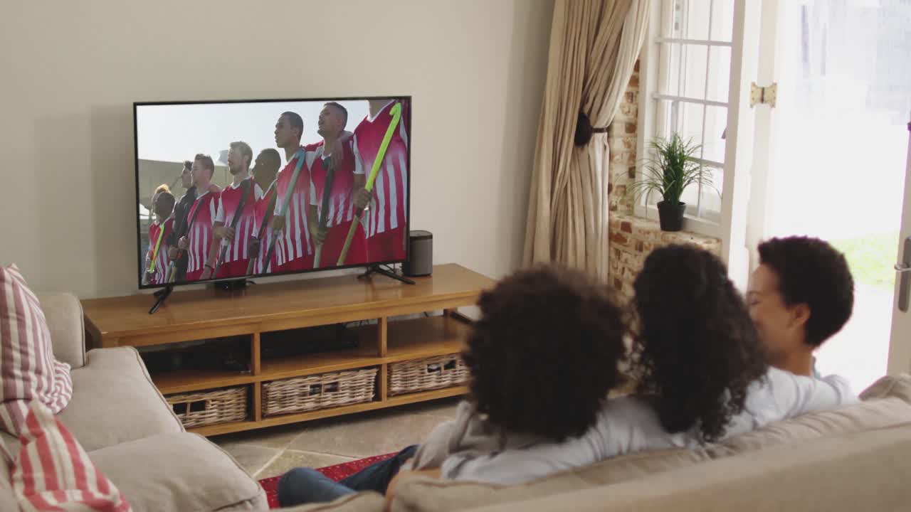 Famiglia felice seduta a casa insieme che guarda una partita di hockey in TV