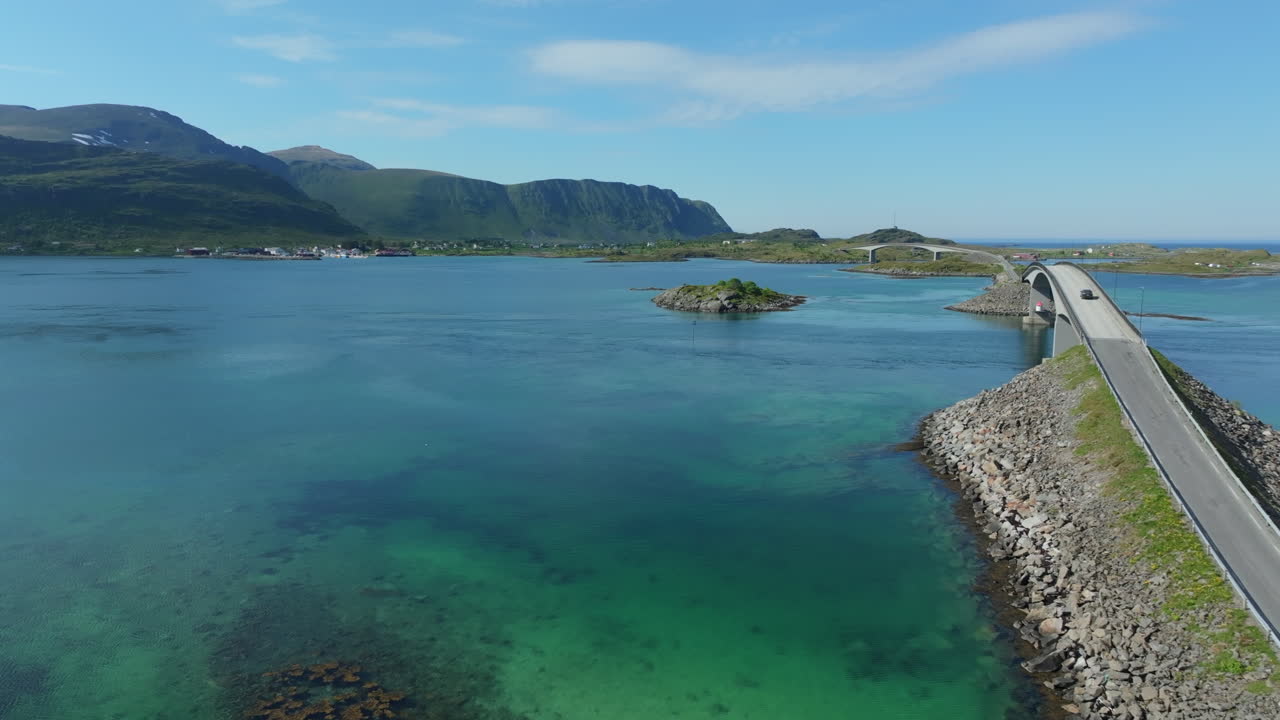 Aerial view of a car driving on a scenic road connecting islands in Norway during a sunny day. The Flakstad bridges in Lofoten Islands, Norway