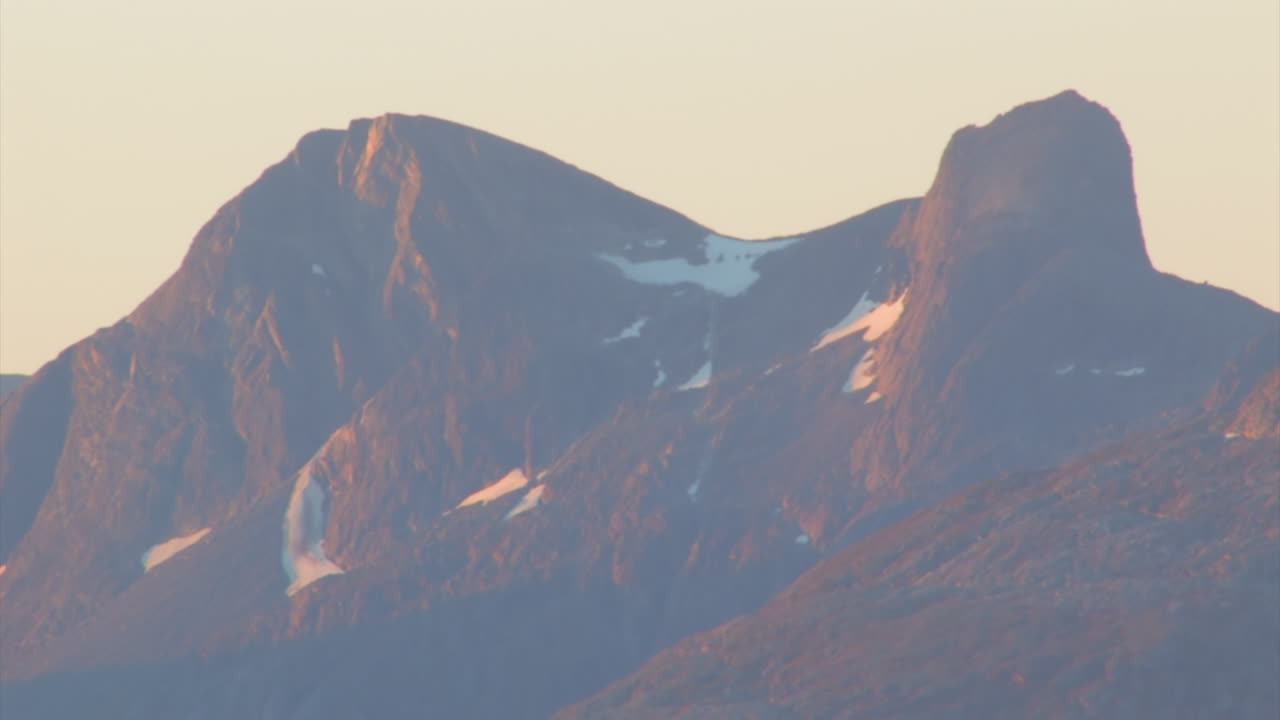가파른 산에 있는 눈은 해가 지는 빛으로  ⁇ 어져 있습니다.