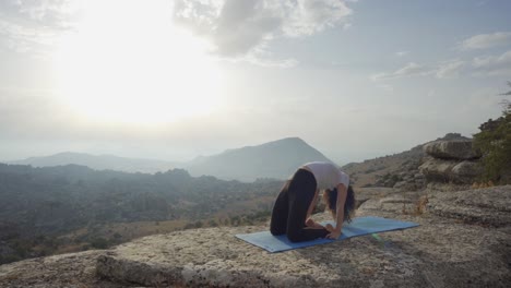 mujer yogui haciendo postura de curva hacia adelante en las montañas
