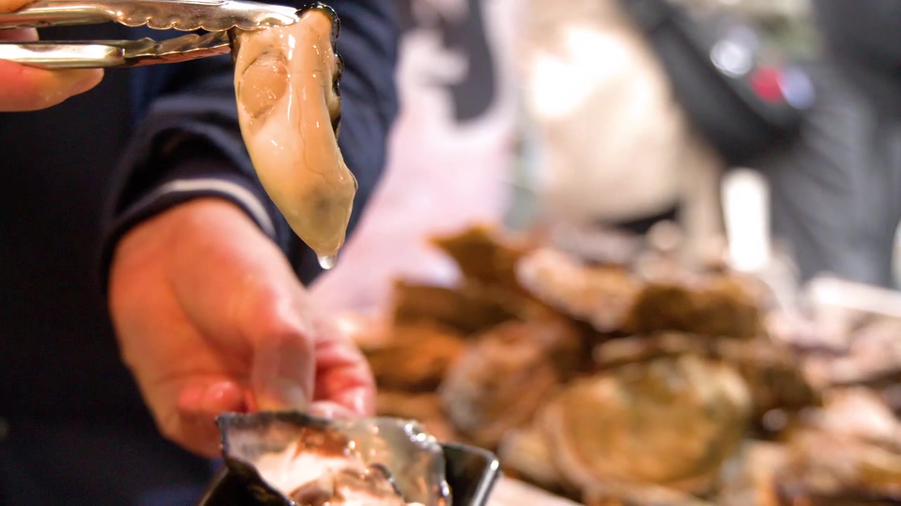 Venditore che serve ostriche fresche e crude al mercato del pesce