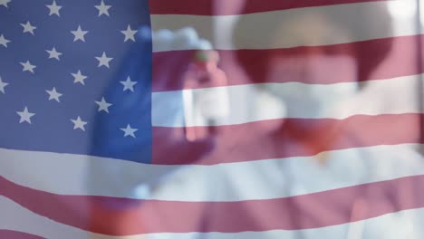 Animation-Der-Flagge-Amerikas-Mit-Ärztin-In-Gesichtsmaske,-Die-Eine-Durchstechflasche-Mit-Covid-Impfstoff-Hält