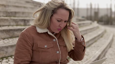 Focused-tired-mature-woman-working-with-laptop-outdoor