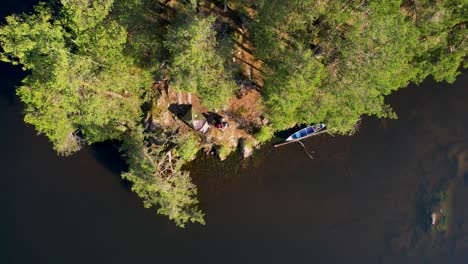 aerial view of forest campsite with tent and canoe by a lake