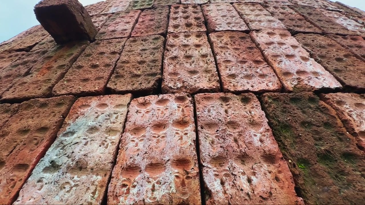 Tracking shot across a weathered red brick surface showing rough masonry texture natural aging and historic architectural character