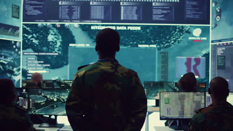 Staff-sergeant-monitoring-satellite-live-imagery-on-a-big-screen