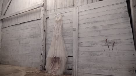 elegant designer wedding gown hanging beautifully on a white wood wall