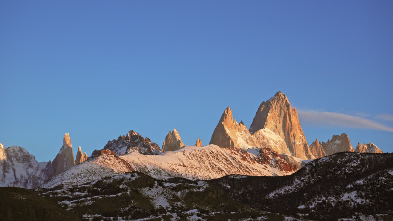 Timelapse panning across Fitz Roy and Cerro Torre peaks as the sun sets over the snow-covered mountains