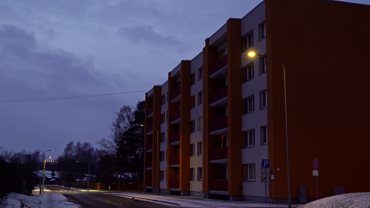 Fachadas de edifícios sob a luz fraca, bloco de apartamentos ao crepúsculo com um corredor noturno solitário ao longe