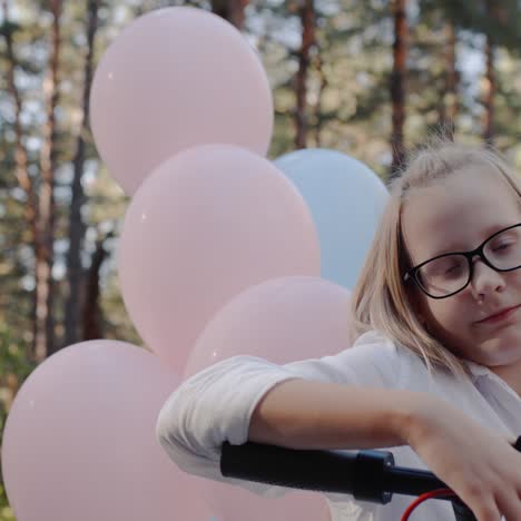 portrait of a cheerful girl at the helm of a scooter and with balloons at the back