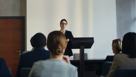 young caucasian businesswoman interacting with people and giving the floor to someone from the audience in a conference room