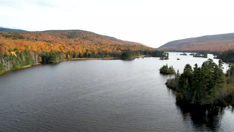 flying over new england lake in mountains during fall changing leaves