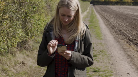 woman using phone on a rural path