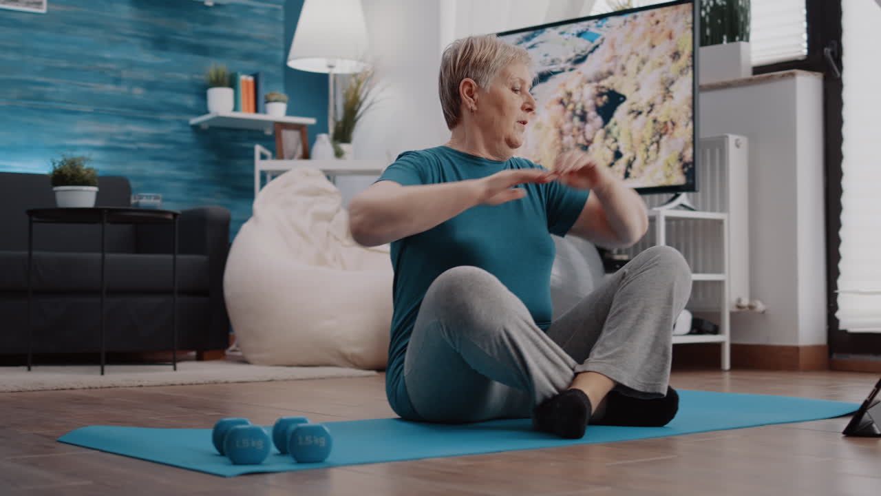 Pensioner watching video of workout lesson with trainer