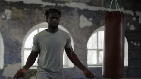 african american man training with skipping rope in and empty hall with large windows