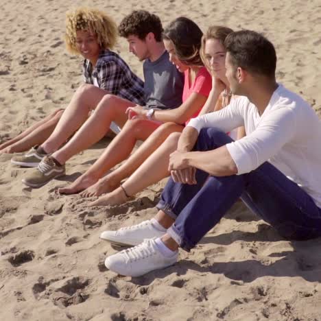 Gruppe-Gemischtrassiger-Menschen,-Die-An-Einem-Strand-Sitzen