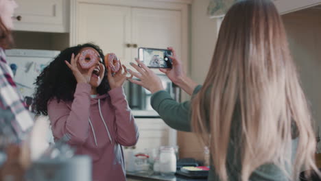 funny teenage girls posing with donuts taking photos using smartphone sharing on social media enjoying hanging out on weekend in kitchen