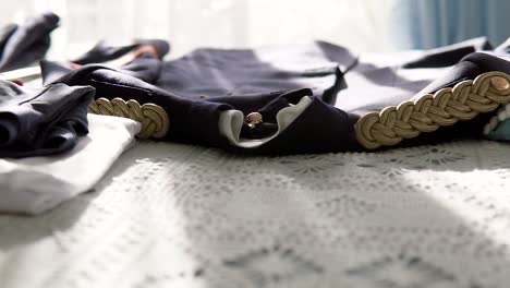 shot of military uniform clothing placed on bed under sunlight