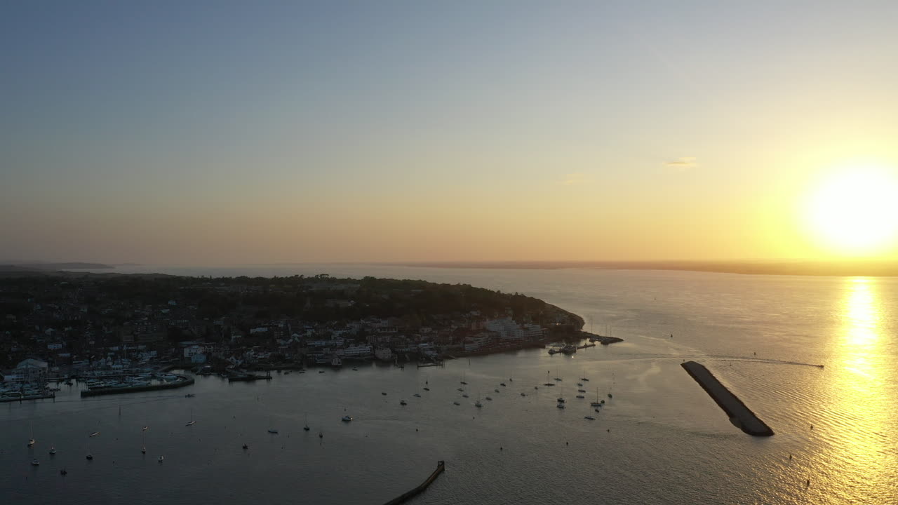 Paesaggio aereo che mostra il sole dorato che tramonta sull'oceano e su una città costiera sull'Isola di Wight.