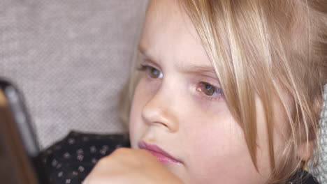 portrait extreme close up of young girl watching tablet or phone, modern world sedentary childhood, shallow depth of field