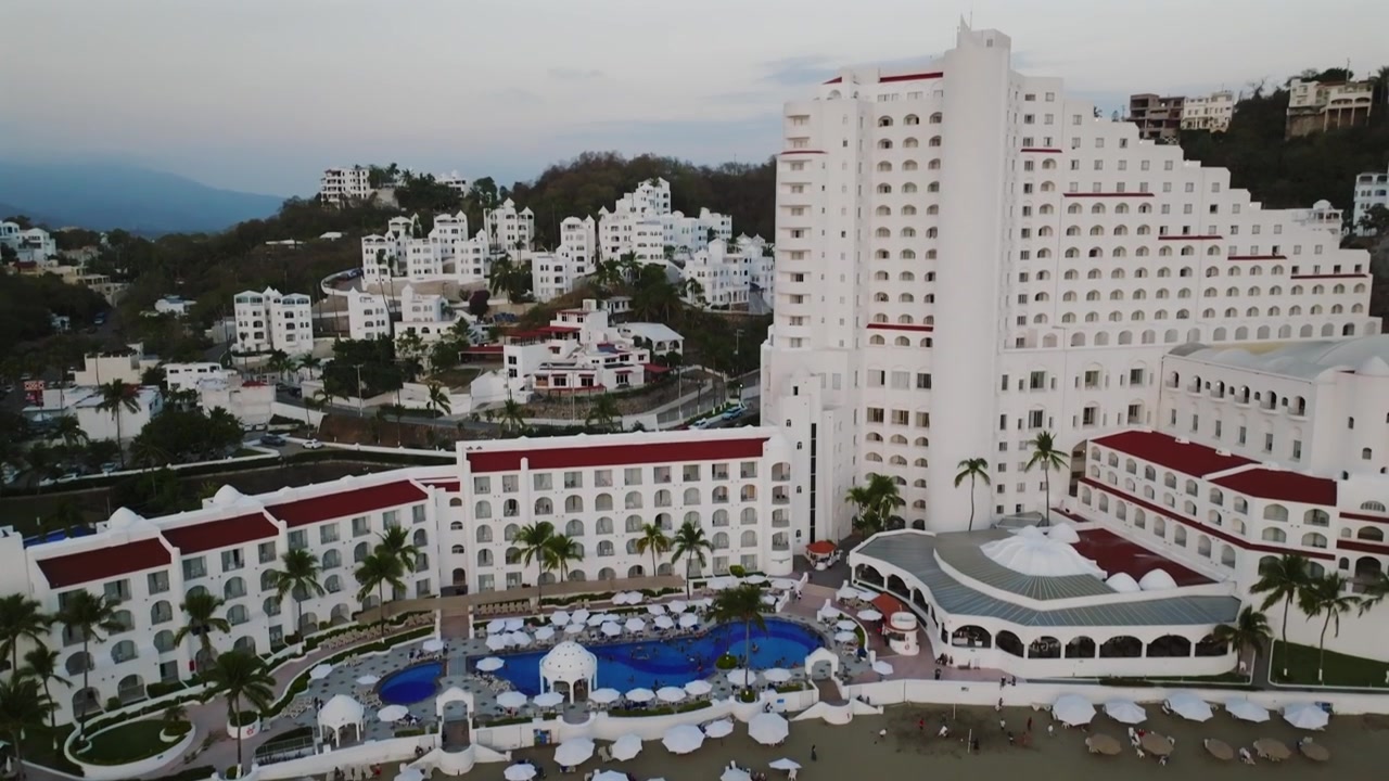Colima, Meksika'da La Audiencia Plajı ve lüks beş yıldızlı Tesoro Manzanillo oteli. Plajın kuşbakışı görüntüsü, bom kolu yükseldiğinde yamaçtaki yerleşim alanını ortaya çıkarıyor.