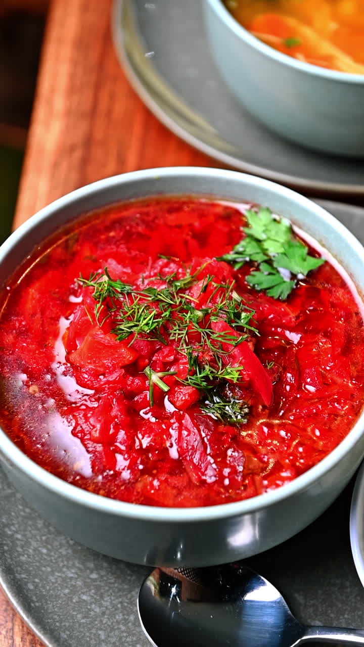 Traditional Ukrainian borscht and chicken soup combo. Two bowls of hot soups — red borscht and chicken broth served together on wooden table