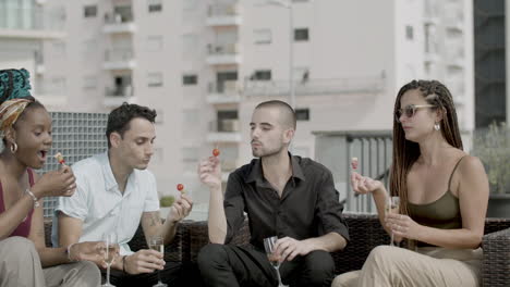 slow motion of cheerful coworkers eating canapes in rooftop cafe