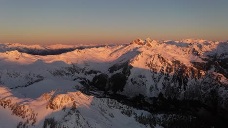 stunning pink colors in the morning on the snowy mountains of bc, canada