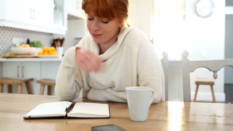 Beautiful-woman-writing-in-organizer-at-table-4k