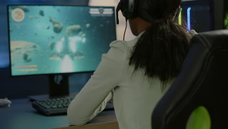 primer plano de una mujer negra competitiva jugando con un joystick jugando al disparo espacial