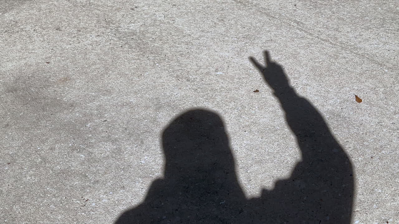 Shadow of man waving peace sign and victory sign with fingers on hand