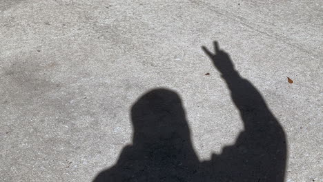 shadow of man waving peace sign and victory sign with fingers on hand