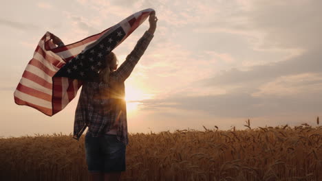 woman with usa flag runs in the sun on a wheat field