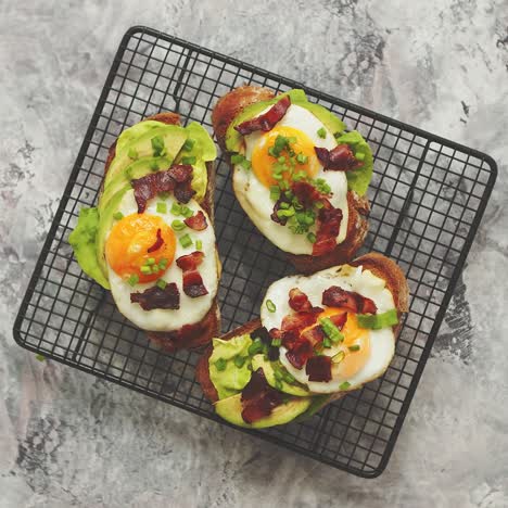 Breakfast-concept--Tasty-delicious-homemade-toasts-with-fried-egg--bacon--avocado--lettuce-and-chive