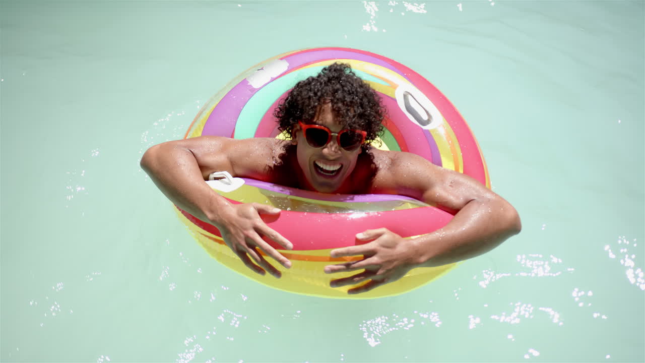 Biracial man enjoys pool time with colorful float at home