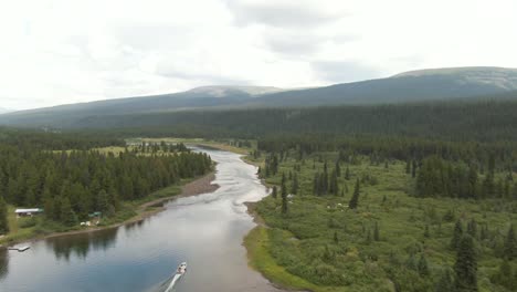 luftaufnahmen, die einem boot folgen, das einen fluss in den bergen und wald in einer wunderschönen abgelegenen umgebung hinuntergeht