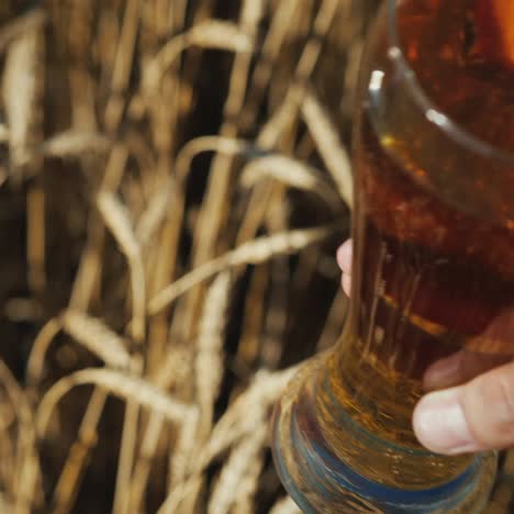 hands with glasses of beer clink glasses in a wheat field 2