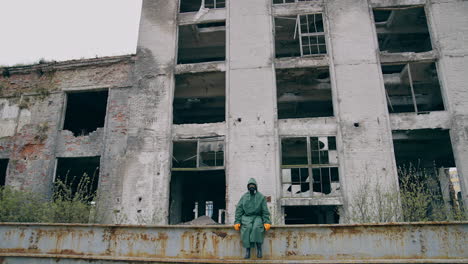 survivor after nuclear chemical incident. man in gas mask near abandoned destroyed building