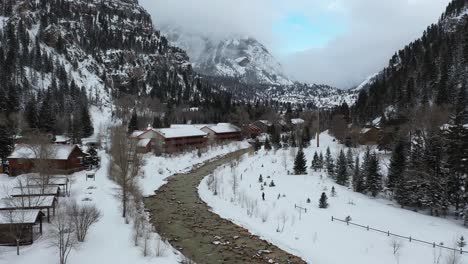 aerial view of lonely person walking on snow by the river in winter landscape of scenic ouray valley, southwestern colorado usa, drone shot on light snowfall