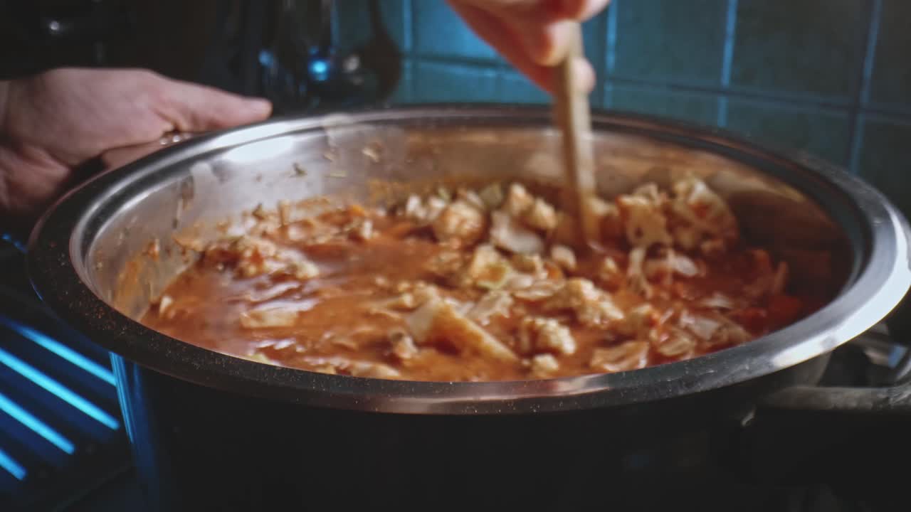 cuchara de madera que se usa para revolver la sopa de verduras en una cacerola de metal y luego se coloca la tapa encima