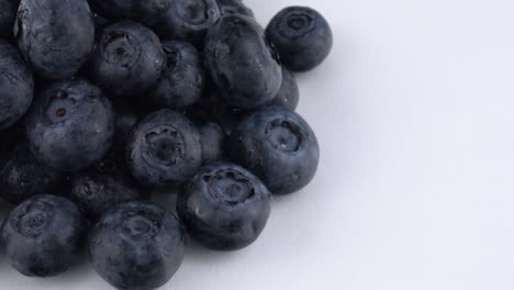 half frame macro of fresh blueberries pile slowly rotates on a white background. isolated. macro.