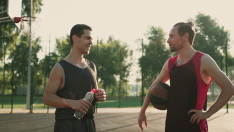 two male basketball players taking a break to drink water and get hydrated