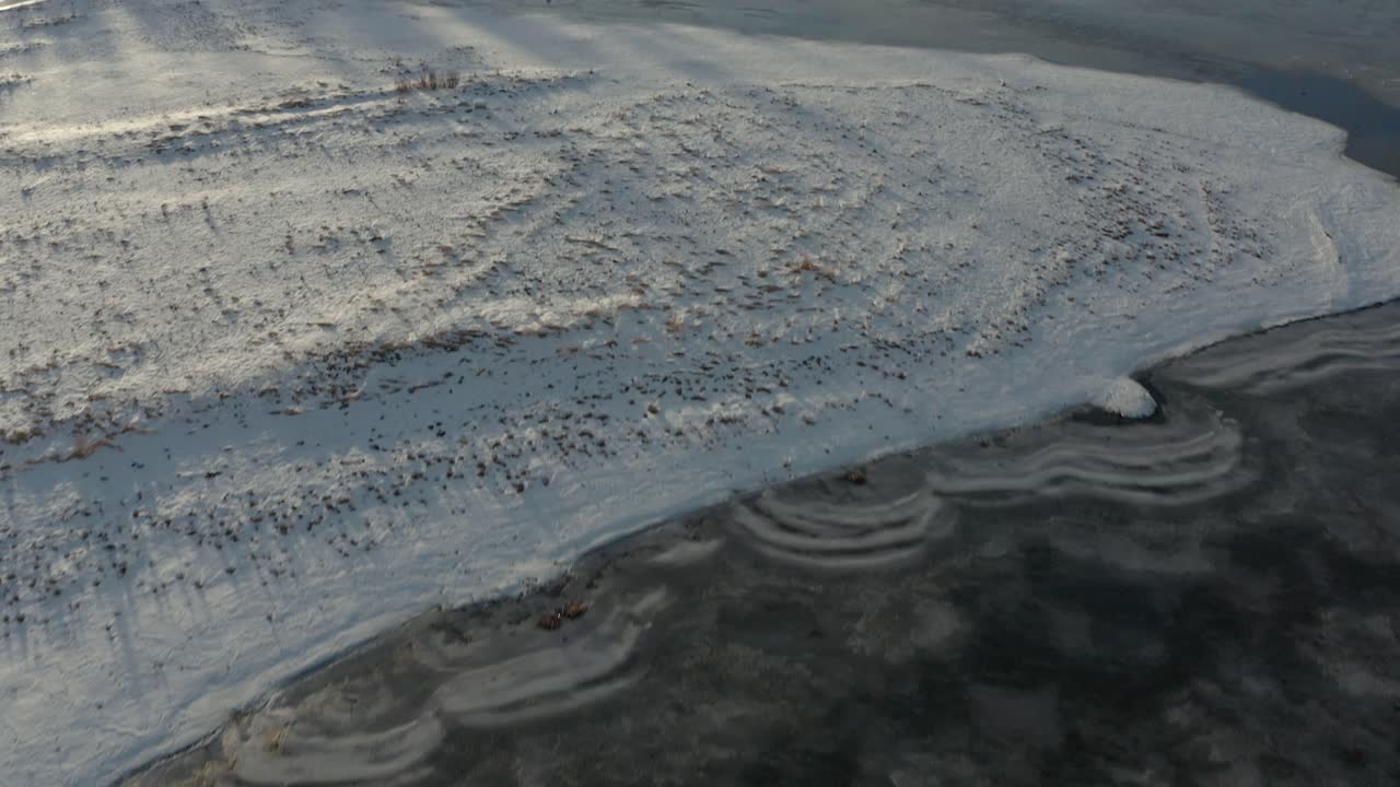 Aerial over shapes and patterns in the ice and then tilting up to reveal frozen lake vista. 4K
