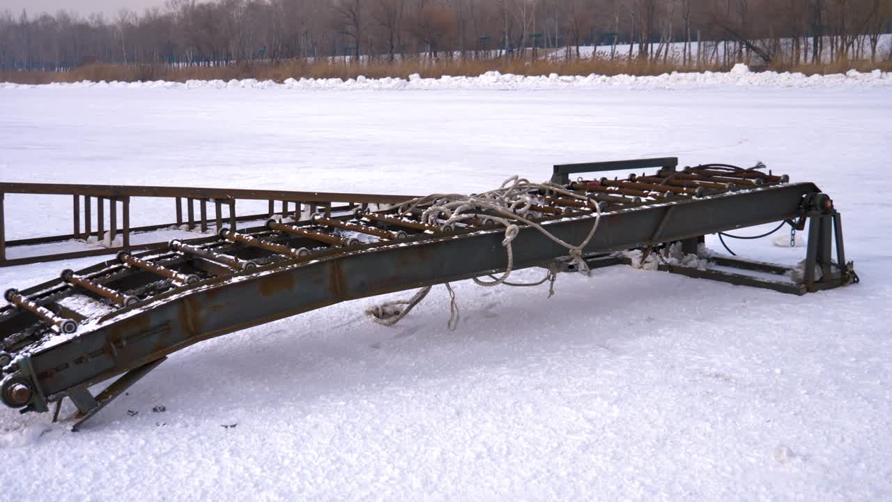 Steel conveyor system used for transporting ice blocks at the Harbin Ice Festival. The rugged industrial machinery sits on a frozen surface, showcasing its engineering and design. China