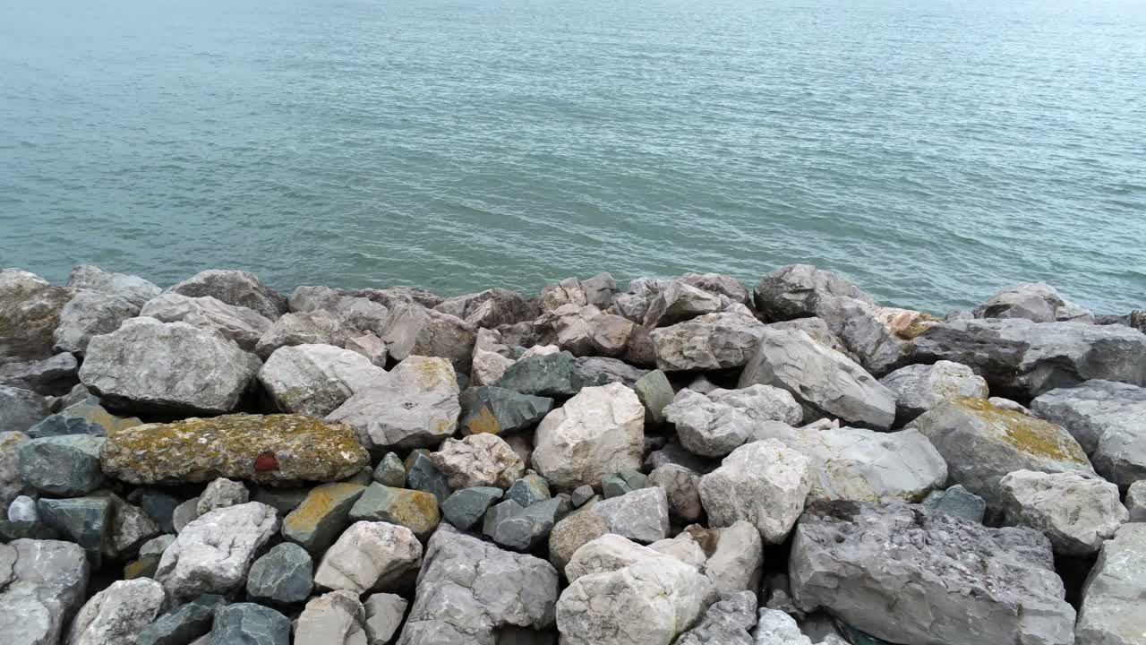 vista aérea por encima de la marea del océano que salpica rompiendo en la costa rocosa de la costa, carro lento a la derecha